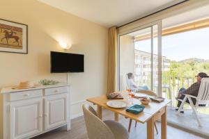 a living room with a table and a tv at Résidences LES HAUTES PLAINES in Gréoux-les-Bains