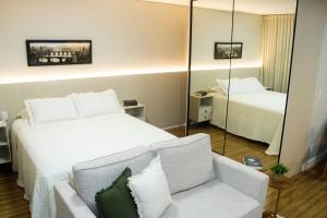a bedroom with a bed and a couch and a mirror at Opus Gyro Vaca Brava Studio Luxo e Aconchego in Goiânia +55 photos