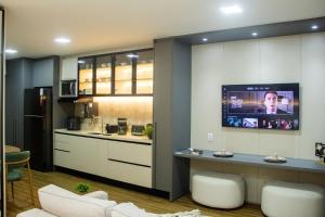a kitchen with a tv on a wall with a counter at Opus Gyro Vaca Brava Studio Luxo e Aconchego in Goiânia