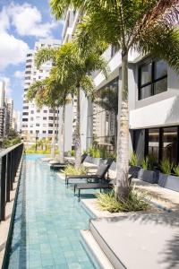 a swimming pool with palm trees next to a building at Opus Gyro Vaca Brava Studio Luxo e Aconchego in Goiânia