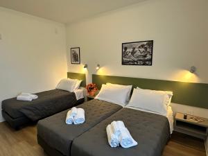 two beds in a hotel room with towels on them at B&B Piano B in Riva del Garda
