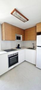 a kitchen with white appliances and wooden cabinets at Oro del Mar iv apartamento 05 in Canyamel