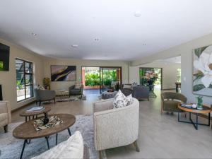 a living room with couches and tables and windows at Pitzer Suites in Midrand