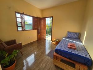a bedroom with a bed and a chair and a window at Chalés Refúgio da Sil 2 in Cavalcante