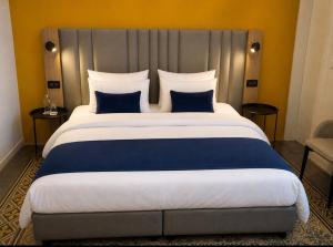 a bedroom with a large bed with blue and white pillows at Mulberry Suites by The LVH Collection in Valletta