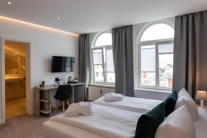 a hotel room with a bed and two windows at Marin Hotel Sylt GmbH in Westerland