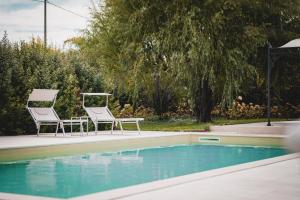 two chairs and a table next to a swimming pool at CuorNice - LG Estate in Ripe San Ginesio