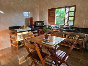 a kitchen with a wooden table and chairs in a room at Chalés Refúgio da Sil 2 in Cavalcante