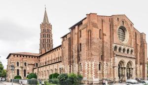 a large brick building with a tower and a church at T2 POMPERTUZAT Calme avec parking in Pompertuzat