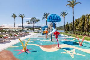 a pool at a resort with palm trees and a slide at VIVA Eden Lago in Port d'Alcudia
