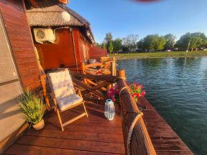 a wooden deck with a chair and a house on the water at Domček na vode 5 in Senec