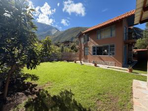 a yard with a house and mountains in the background at Auka Boutique in Urubamba