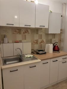 a kitchen with white cabinets and a sink at Mieszkanie BLOK in Złotów