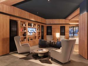 a living room with two chairs and a television at Swissôtel Resort Kolasin in Kolašin