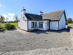a white house with a gravel driveway at Cahir Cottage in Ballinrobe