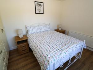 a bedroom with a white bed and two night stands at Cahir Cottage in Ballinrobe