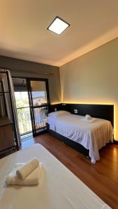 a hotel room with two beds and a window at Sobrado inteligente, A C, TVs Smart e garagem in Toledo