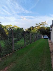 a fence with a car parked on the side of a road at Pesqueiro Rancho dos Reis in Aquidavana