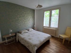 a bedroom with a bed and a chair and a window at Maison Angers bord de loire, rue Jules Quelin in Les Ponts-de-Cé