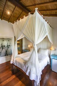 a bedroom with a canopy bed with white curtains at Monkey Casa Hotel in Trancoso +99 photos
