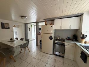 a kitchen with a white refrigerator and a table and a table and chairs at Maison Dans les nuages in Oderen