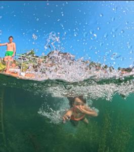 a child swimming in the water in front of a boat at Rosa B&B in Lin
