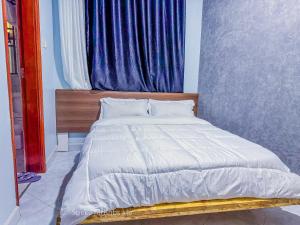 a bedroom with a white bed with a window at Speke homes full apartment!!! in Kabale