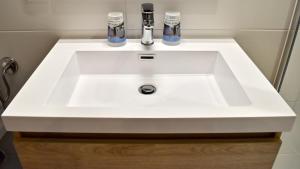 a white bathroom sink with two faucets on it at Le Vieux Noyer in Réaux