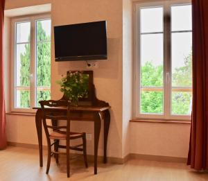 a table with a chair and a television on a wall at Le Vieux Noyer in Réaux