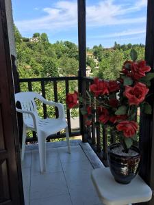 a white chair and a vase with red roses on a porch at Sofia Rooms in Kissos