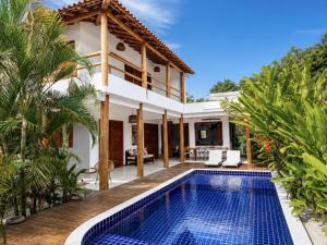 a villa with a swimming pool in front of a house at CASA SIMONI Trancoso in Trancoso