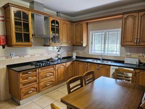 a kitchen with wooden cabinets and a wooden table at Vila das Pétalas in Portimão