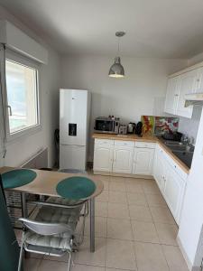 a kitchen with a table and a white refrigerator at Studio climatisé avec vue mer in Bastia