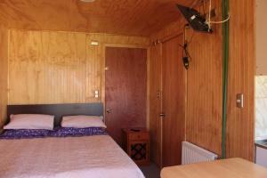 ein Schlafzimmer mit einem Bett und einer Holzwand in der Unterkunft Departamentito Austral in Puerto Montt