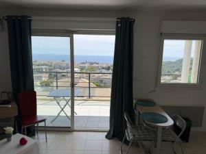 a room with a table and chairs and a large window at Studio climatisé avec vue mer in Bastia