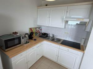 a kitchen with white cabinets and a sink and a microwave at Studio climatisé avec vue mer in Bastia