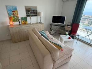 a living room with a couch and a television at Studio climatisé avec vue mer in Bastia