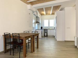 a kitchen with a wooden table and chairs and a refrigerator at Homenfun Vila Badalona in Badalona