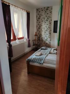 a small bedroom with a bed and two windows at Guest Zimmer Nora in Zamárdi