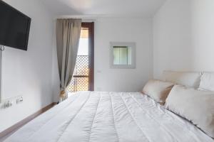a white bed in a white room with a window at Casa Claudia in Elmas