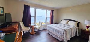 a hotel room with a bed and a desk and a window at St Ann's Motel & Cottage in Baddeck