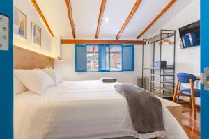 ein Schlafzimmer mit einem großen weißen Bett mit blauen Akzenten in der Unterkunft LA RAMBLA Hotel Boutique - Cusco in Cusco