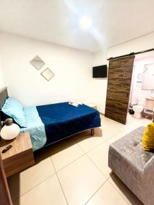 a bedroom with a blue bed and a couch at Hotel Fuente Real Popayán in Popayan