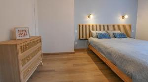 a bedroom with a bed and a dresser with blue pillows at Chez nenette in Prugny
