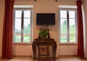 a dining room with a table and a tv and windows at Le Vieux Noyer in Réaux +25 photos