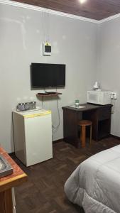 a bedroom with a bed and a desk with a tv at No7 Mc Intyre Guest House in Sasolburg