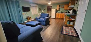 a living room with a blue couch and two chairs at St Ann's Motel & Cottage in Baddeck