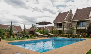 a swimming pool in front of a house at WOODSY Resort in Nanyuki