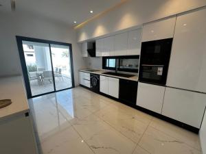 a kitchen with white cabinets and black appliances at Villa Donia in Mezraya