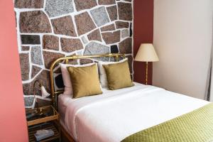 a bedroom with a bed with a stone wall at Auberge la Rosepierre bistro Henri in Grandes-Bergeronnes